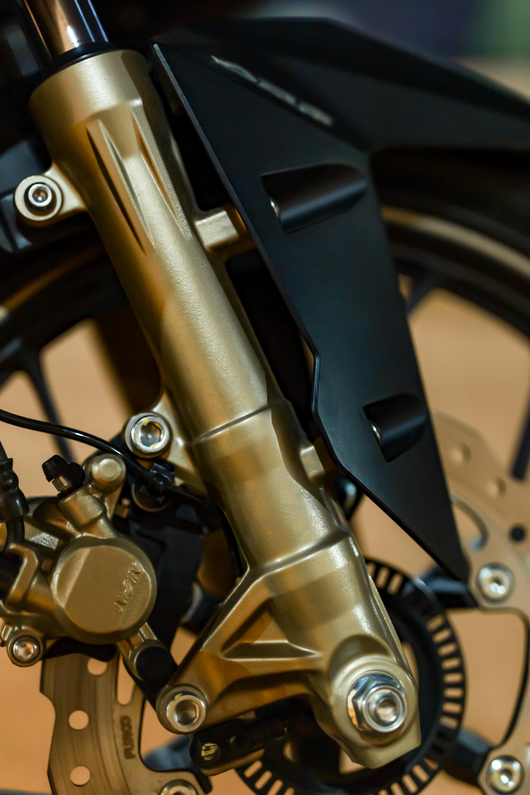 Closeup of modern motorbike wheel with brake panel and fork tube fixed with screws