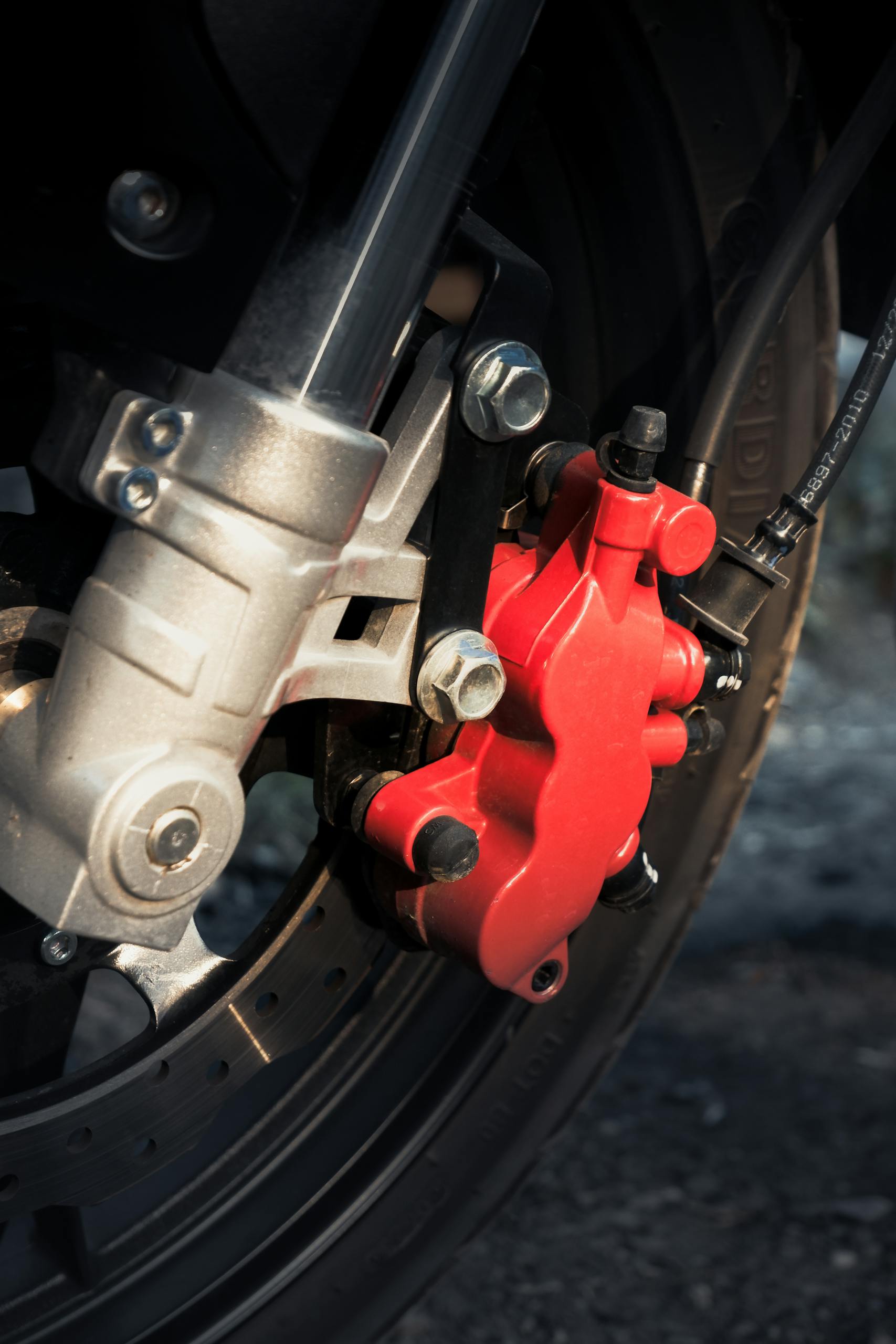 Detailed close-up of a red motorcycle brake caliper on a wheel.